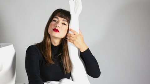 A woman sitting on a bed with a white sheet covering her face